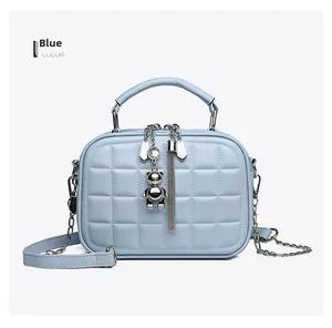 Detailed view of light blue quilted crossbody bag with silver bear and tassel charms