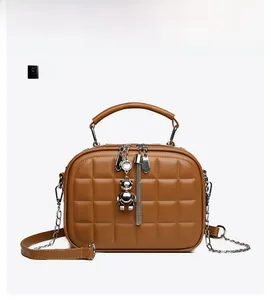 Detailed front view of brown quilted crossbody bag with silver bear charm and chain strap
