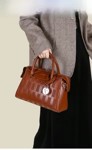 Détail du sac à main en cuir marron avec texture gaufrée et pendentif métallique lettre F