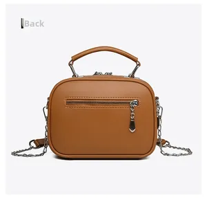 Rear view of brown crossbody bag featuring cylindrical top handle and zip back pocket
