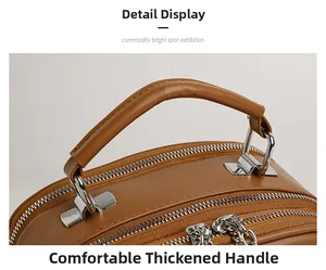 Detail showing the thick rounded handle and dual silver zippers on the brown leather bag