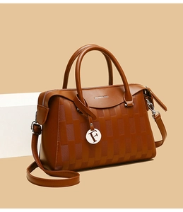 Détail du sac à main marron caramel avec texture tressée et un pendentif métallique lettre F
