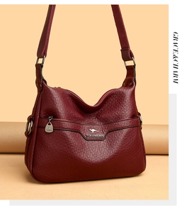 Detailed view of wine red lychee pattern leather shoulder bag with kangaroo metal logo