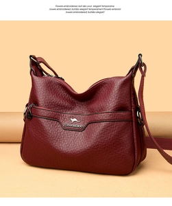 Detail of burgundy lychee grain leather handbag with metallic kangaroo logo and zipper