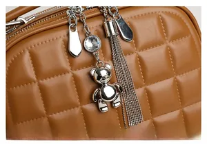Detailed macro shot of brown quilted leather bag with bear charm and silver tassel zipper