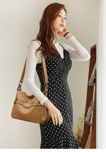Detail of brown litchi pattern shoulder bag with metal logo on high-quality leather surface