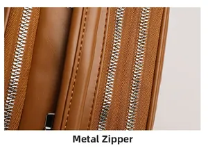 Detail of three-layer silver metal zippers on brown lychee pattern leather crossbody bag