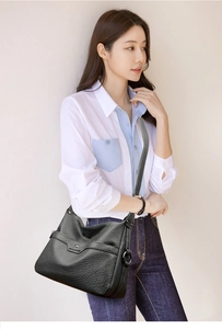 Detailed side view of a black pebble-textured crossbody bag on a model in studio