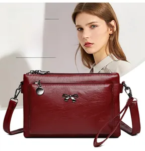 Makroaufnahme einer roten Handtasche mit Kieseltextur und Metall-Schmetterlingsornament