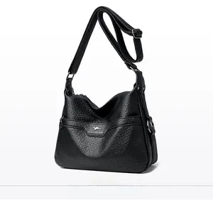 Detail view of black textured leather crossbody bag featuring kangaroo logo and wide strap