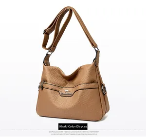 Detailed macro view of khaki lychee texture leather shoulder bag with silver kangaroo icon