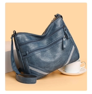 Dettaglio della borsa a tracolla in morbida pelle grigio-blu con cerniere multiple e strass