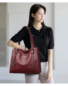 Dettaglio della borsa tote in pelle bordeaux con logo dorato e pendente in metallo