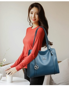 Dettaglio ravvicinato della borsa tote in pelle blu scuro con logo metallico a canguro