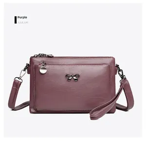 Detailansicht der lila Ledertasche mit goldener Metallschleife und verstellbarem Gurt
