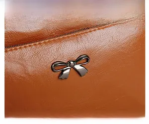 Detailaufnahme der braunen Ledertasche mit Litschi-Muster, Metallschleife und Reißverschluss
