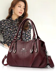 Detailed macro of the wine red lychee grain texture and gold kangaroo metal logo on handbag