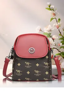 Gros plan du sac bandoulière marron avec rabat rouge et logo métallique circulaire
