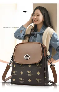 Détail d'un sac bandoulière imprimé avec logo métallique et chaîne sur un mannequin