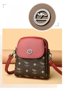 Détail du sac bandoulière en cuir rouge et marron avec logo kangourou en métal doré