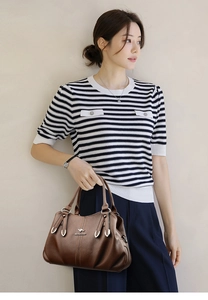 Side view of dark brown faux leather handbag featuring lychee texture and metallic logo