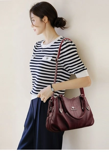Burgundy faux leather handbag shown on model with lychee grain and kangaroo logo detail