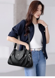 Close-up of soft black leather handbag with silver kangaroo logo and fine grain texture