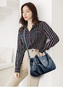 Close-up of navy blue litchi pattern leather handbag with silver kangaroo logo on strap