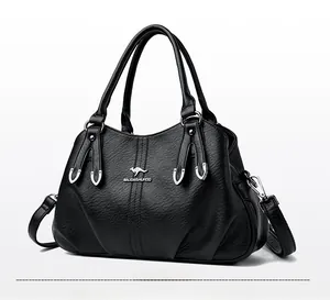 Detailed view of black textured leather handbag with gold kangaroo logo and dual handles