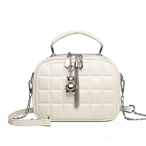 White quilted crossbody bag with silver bear charm and leather chain strap on white background