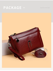 Detail of wine red faux leather bag with multi-layer zippers, strap, and wristlet
