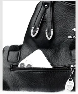 Detail of soft leather handbag with reinforced stitching, logo, and rear anti-theft pocket
