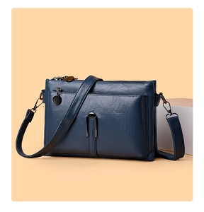 Detailed view of navy blue crossbody bag with lychee texture and multi-zipper compartments