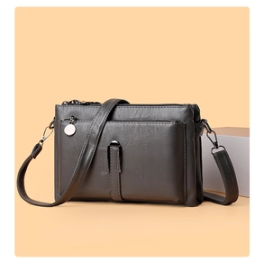 Close-up of charcoal grey faux leather bag featuring multi-zipper layers and U-shaped metal trim