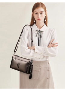 Detail showing metallic brown leather shoulder bag with zipper and vertical buckle strap