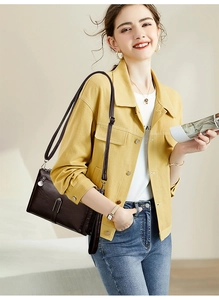Detail of dark brown crossbody bag with metallic accents and glossy finish on model