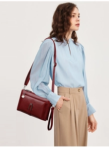 Detail of burgundy leather crossbody bag with silver hardware and adjustable strap