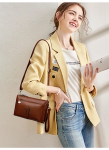 Detail of brown leather crossbody bag featuring wax texture and metal zip puller