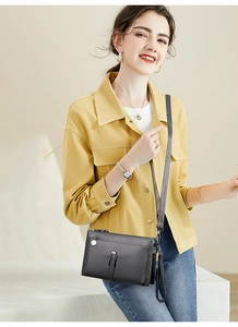 Charcoal grey matte leather crossbody bag styled with a bright yellow jacket outfit