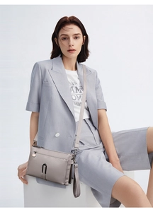 Detail of grey leather crossbody bag featuring metal zip pocket and U-shaped decor