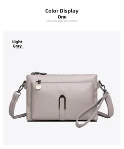 Close-up of light grey textured leather crossbody bag with dark gunmetal hardware accents