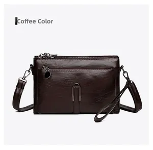 Detail view of coffee leather crossbody bag featuring multi-layer zipper pockets and buckles