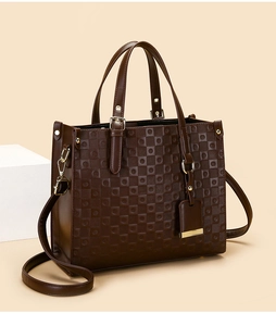 Détail d'un sac cabas marron foncé gaufré en similicuir avec des ferrures dorées