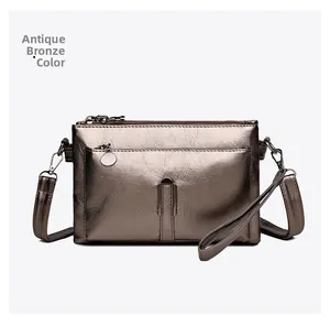 Detail of a bronze metallic shoulder bag showing texture, wrist strap, and zip closure