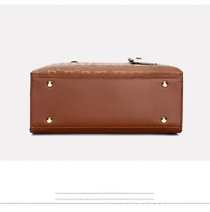 Détail du bas de sac en cuir marron avec quatre pieds de protection dorés et côtés gaufrés