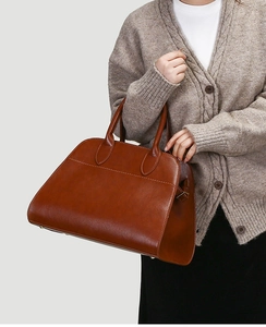 Retro brown tote bag with large capacity held by model featuring side buckle details