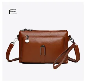 Detail of yellowish brown crossbody bag with lychee grain texture and silver zippers