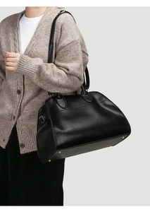 Detailed macro view of black leather tote bag with gold metal rivets and adjustable strap