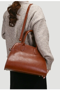 Side view of a vintage brown leather tote bag worn by a model for size and style reference