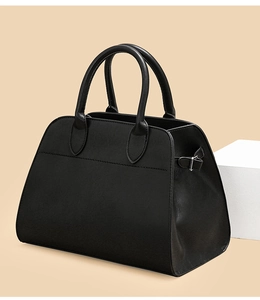 Detail view of the sleek matte black leather tote with sturdy rounded handles and buckle